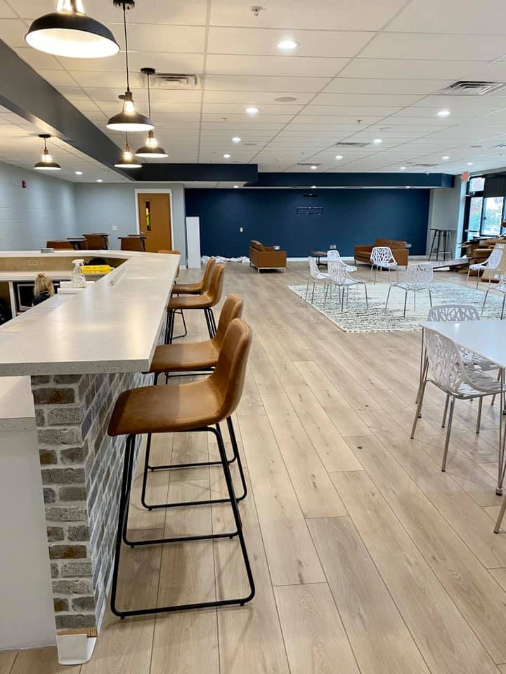 Modern cafeteria with high tables, stools, and scattered seating in a bright, open room