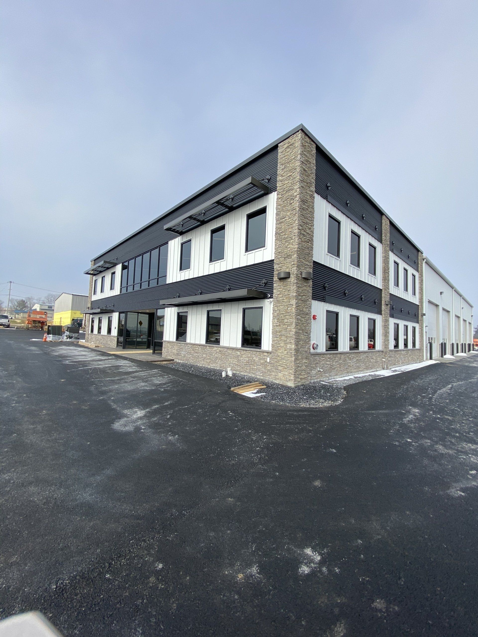 Two-story white building with dark trim on a paved lot under a cloudy sky