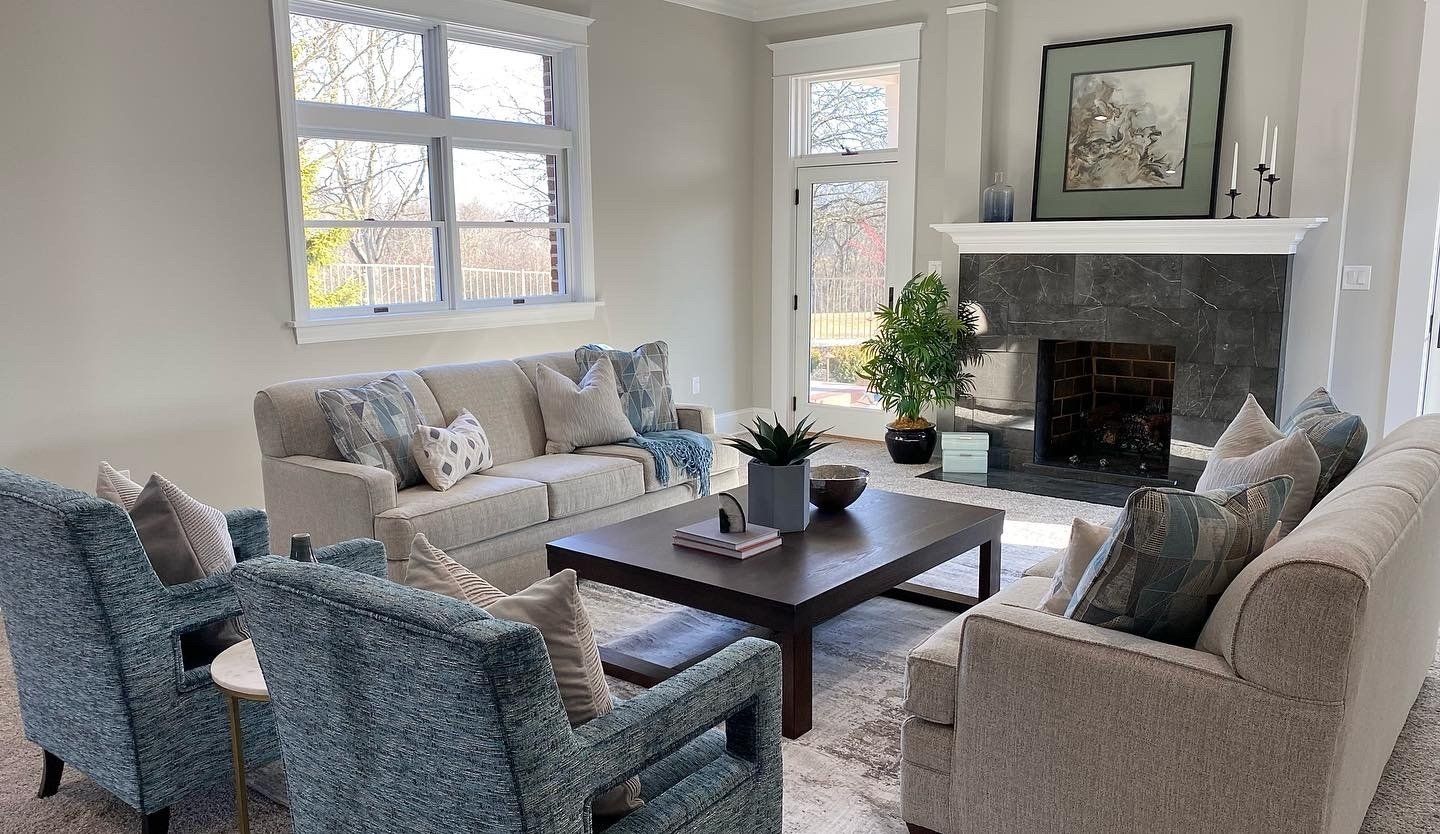Bright living room with two armchairs, sofa, coffee table, fireplace, and large windows