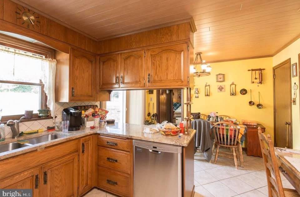Wooden kitchen with stainless sink, open window, and a small dining area beyond.