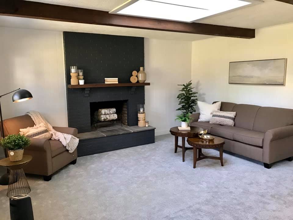 Cozy living room with gray sofa, fireplace, armchair, and small wooden coffee tables
