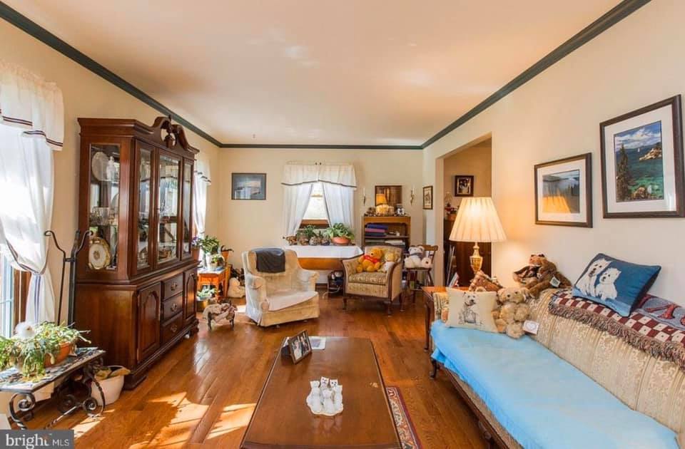 Cozy living room with wood floors, glass cabinet, blue sofa, armchair, lamps, and framed wall art.