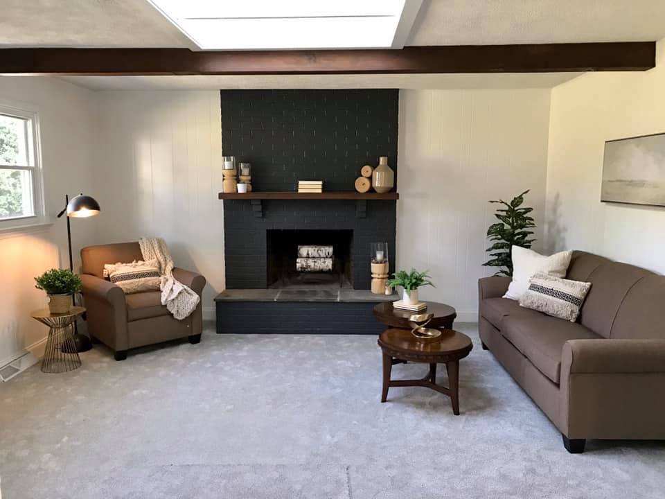 Cozy living room with two sofas, fireplace, coffee table, and neutral decor.