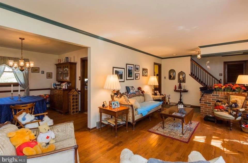 Cozy living room with wood floors, fireplace, blue sofa, lamp, and staircase in the background