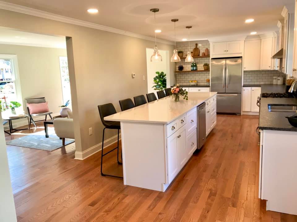 Bright open kitchen with island, white cabinets, stainless steel appliances, and hardwood floors