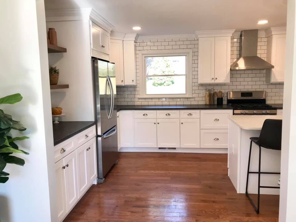 Bright white kitchen with stainless fridge, tiled backsplash, and warm wood floors
