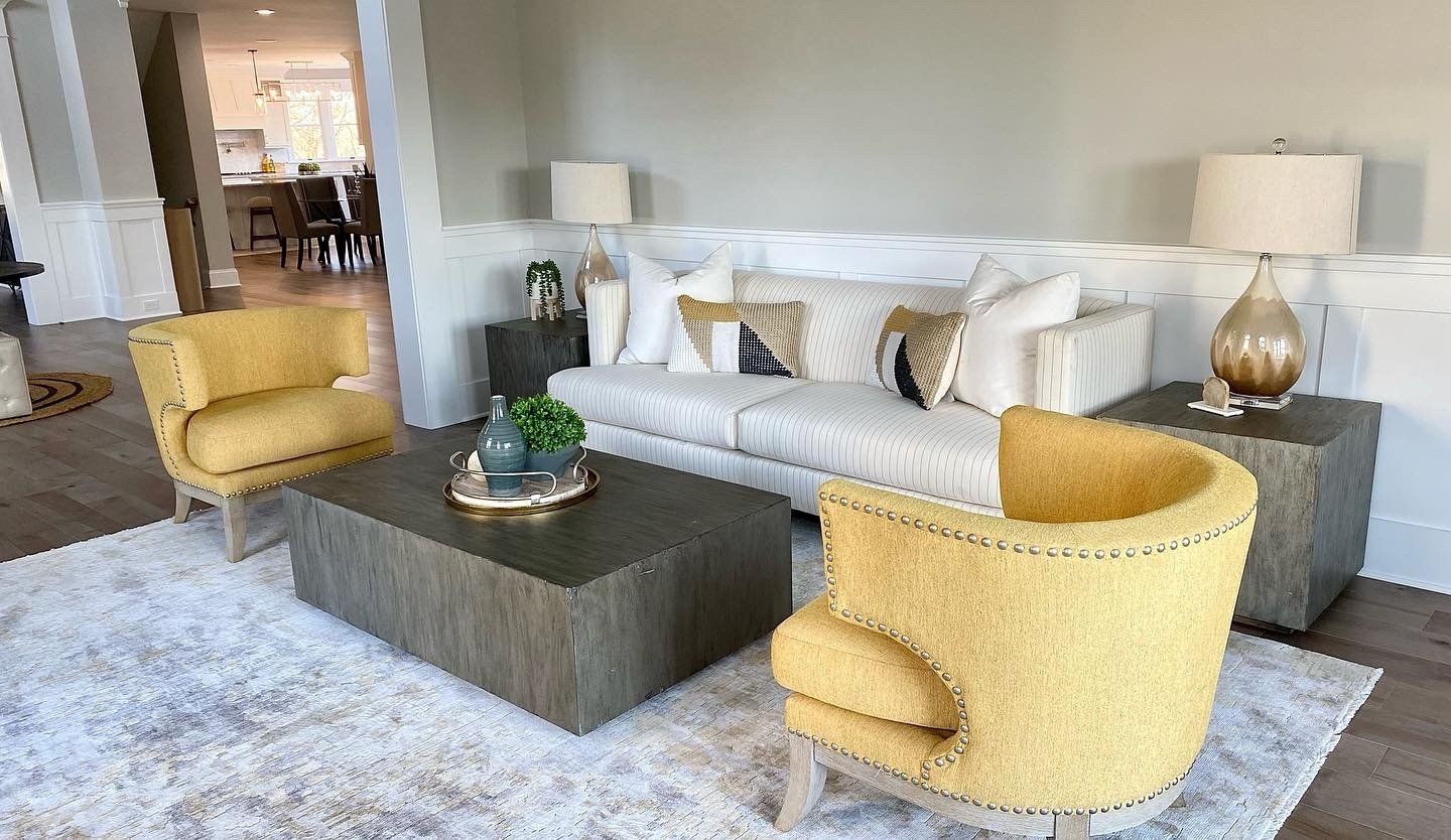 Elegant living room with gray sofa, yellow chairs, coffee tables, lamp, and light rug