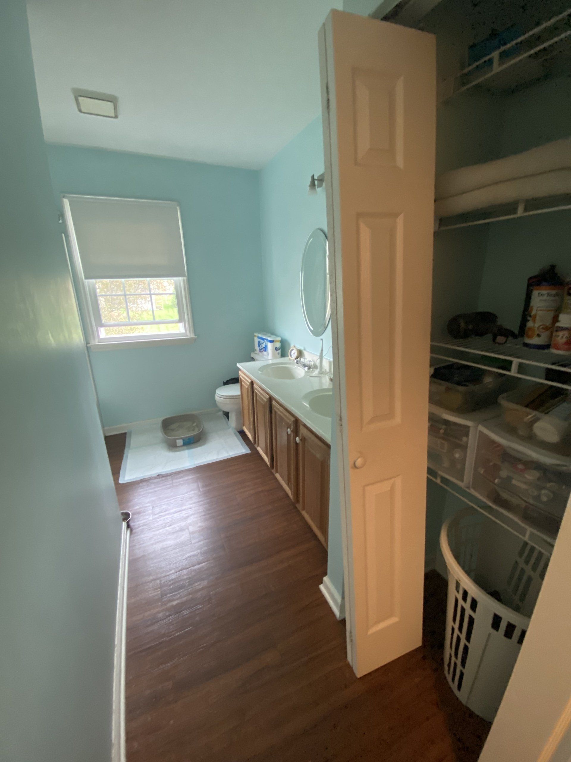 Narrow laundry room with sink, cabinets, washer and dryer, light blue walls, and a window at the end.