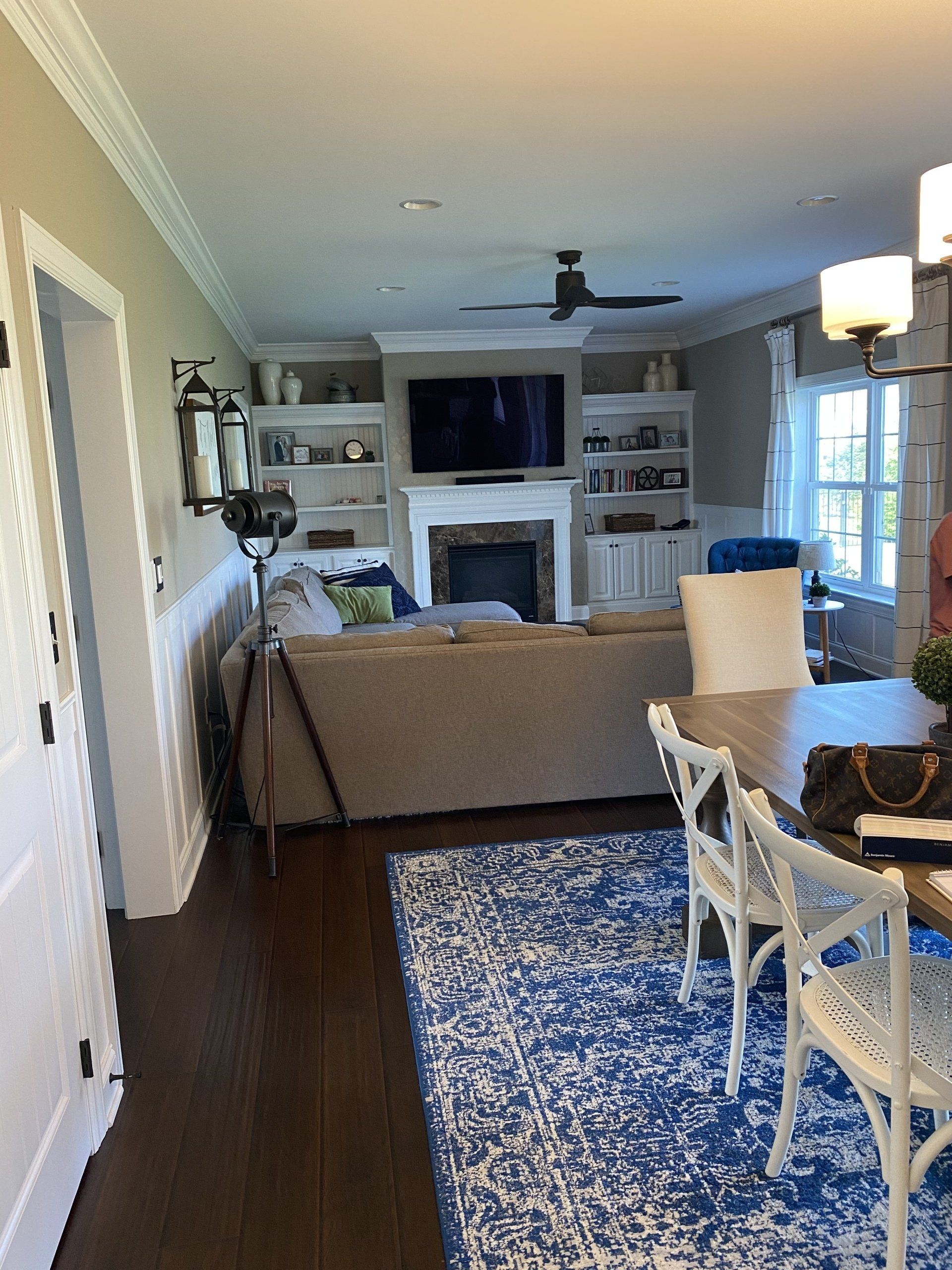 Living room with a fireplace, TV, sofa, dining table, and blue patterned rug