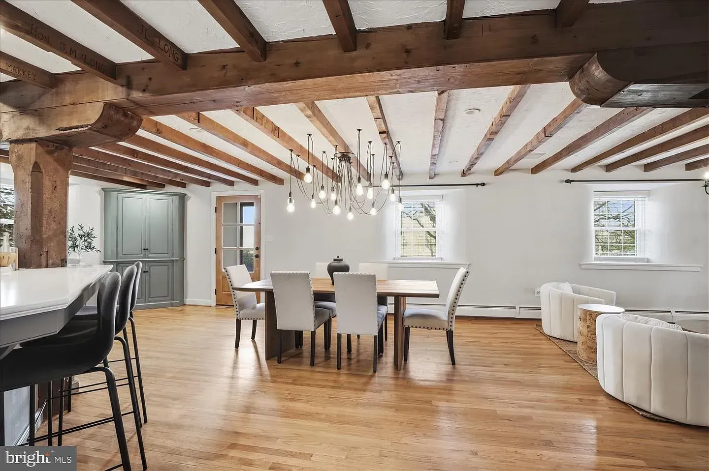 Bright dining room with exposed wooden beams, white walls, and modern chairs on hardwood floors