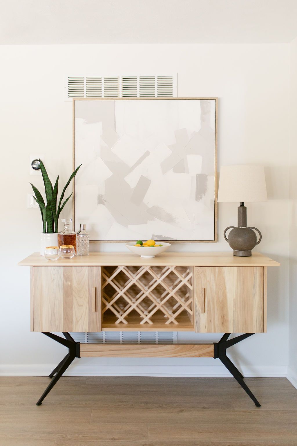 Modern console table with decor, mirror, lamp, and plant against a white wall
