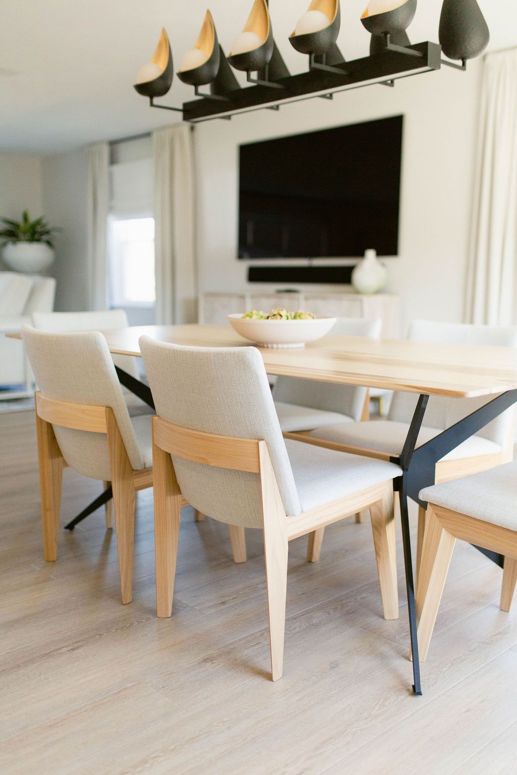 Modern dining room with white chairs, wooden table, and wall-mounted TV