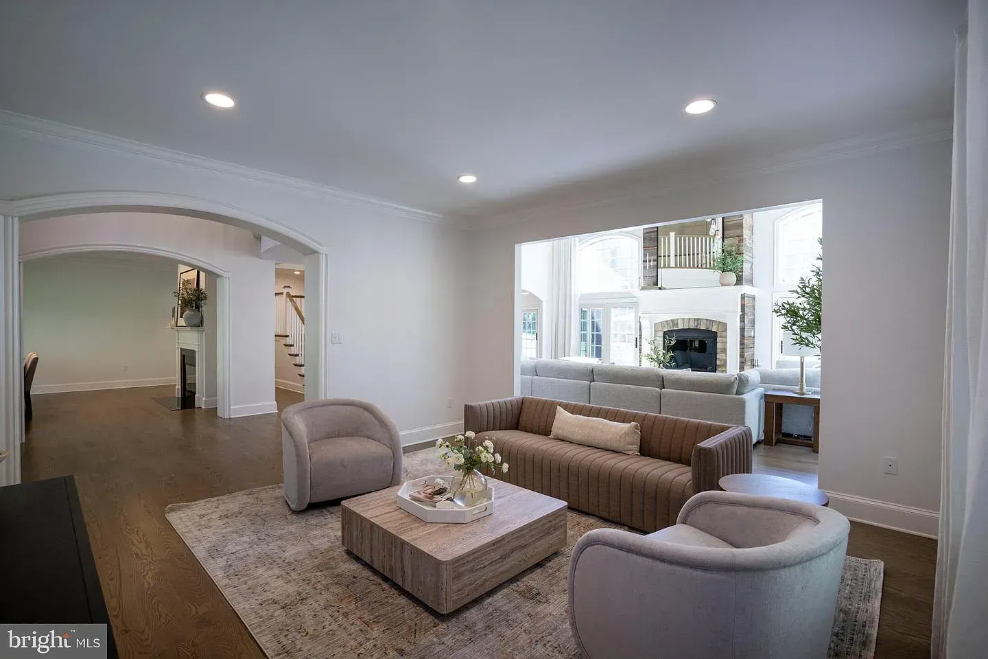 Bright modern living room with gray chairs, sofa, coffee table, and large window seat niche.