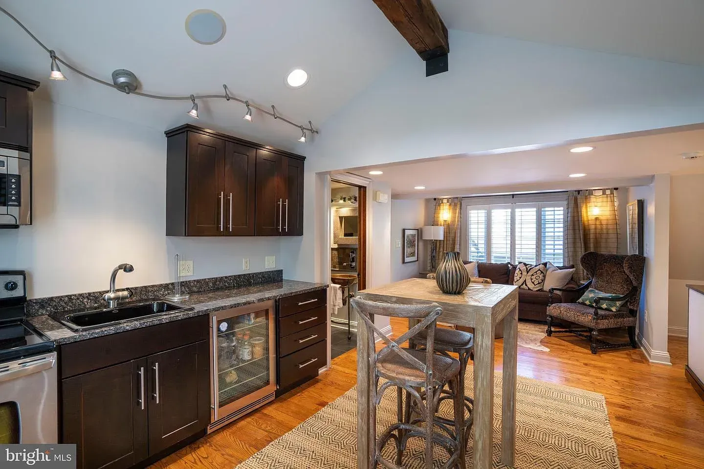 Open kitchen and dining area with dark cabinets, granite counter, island, and hardwood floors