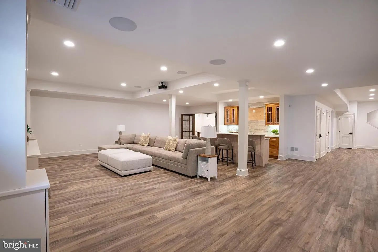 Spacious open-concept living room with white sectional, wood floors, and recessed ceiling lights