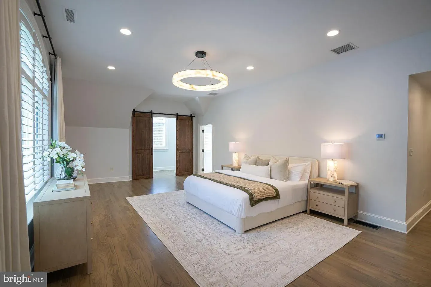 Modern bedroom with a large bed, rug, wood floors, and recessed ceiling lights