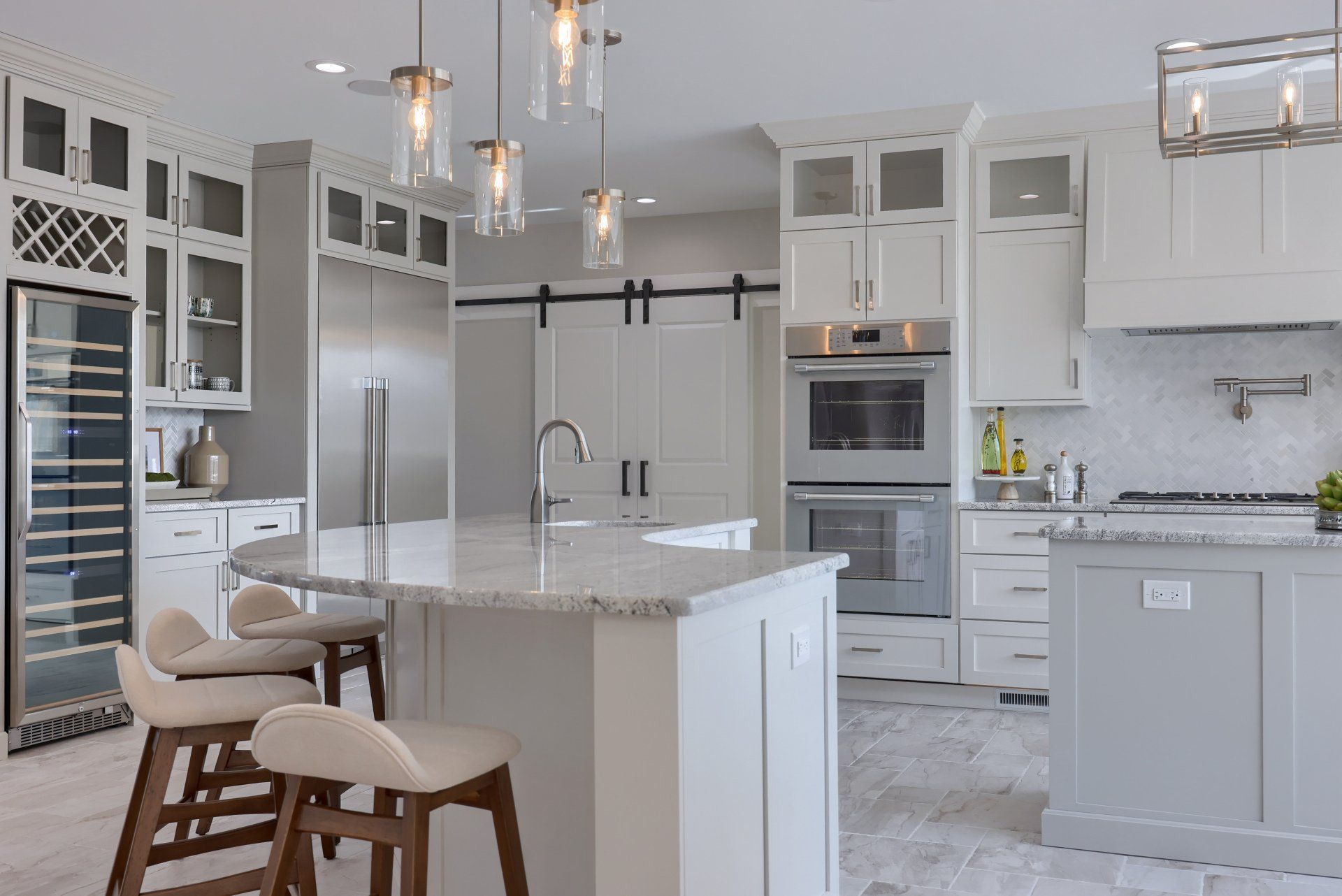 Bright modern white kitchen with island, pendant lights, stainless appliances, and bar stools