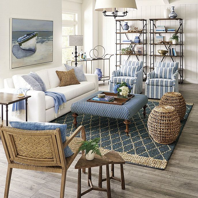 Bright coastal living room with white sofa, blue accents, wicker chairs, and patterned rug