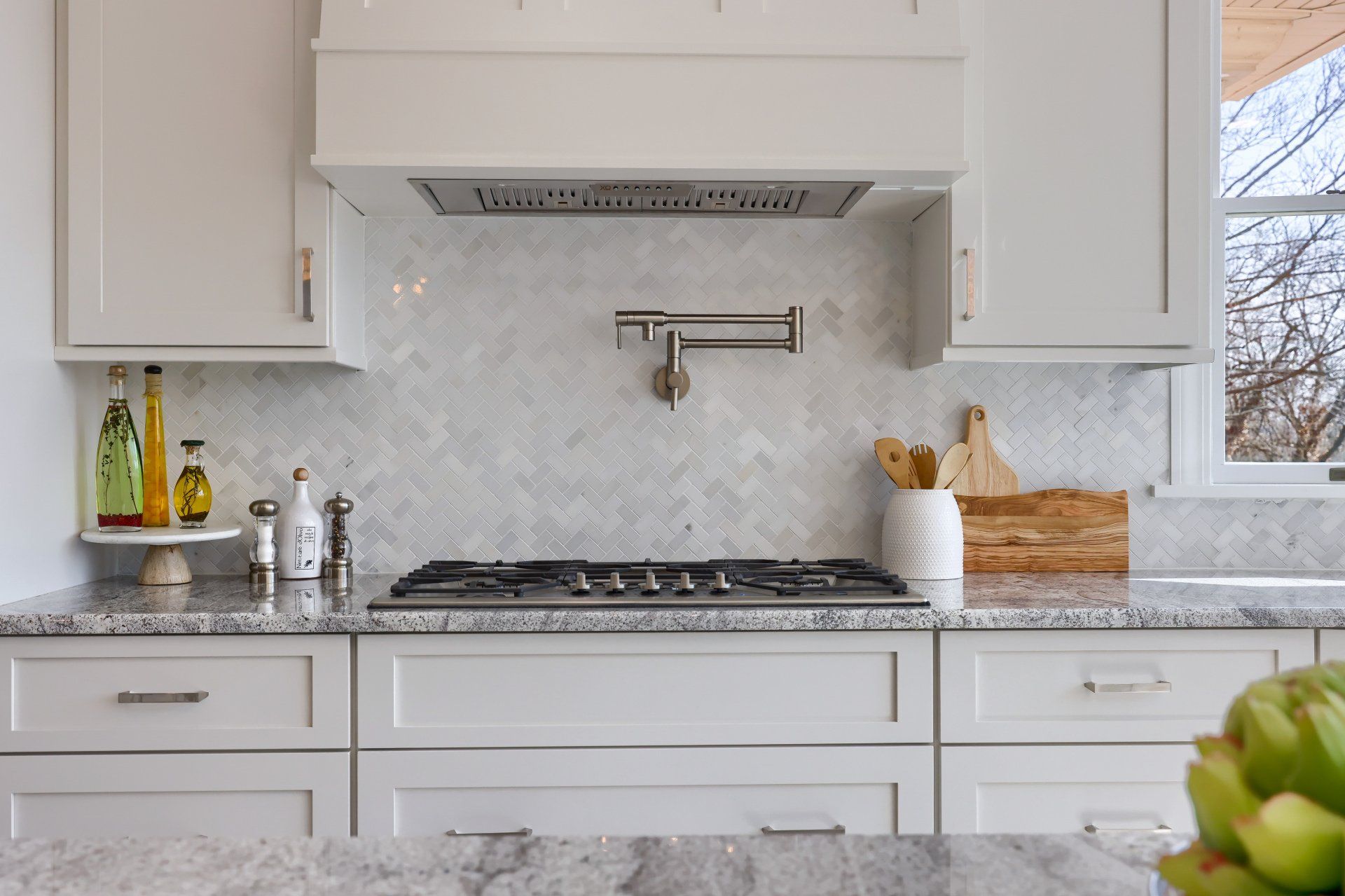 Bright white kitchen with marble countertops, gas range, and fruit bowl on the counter