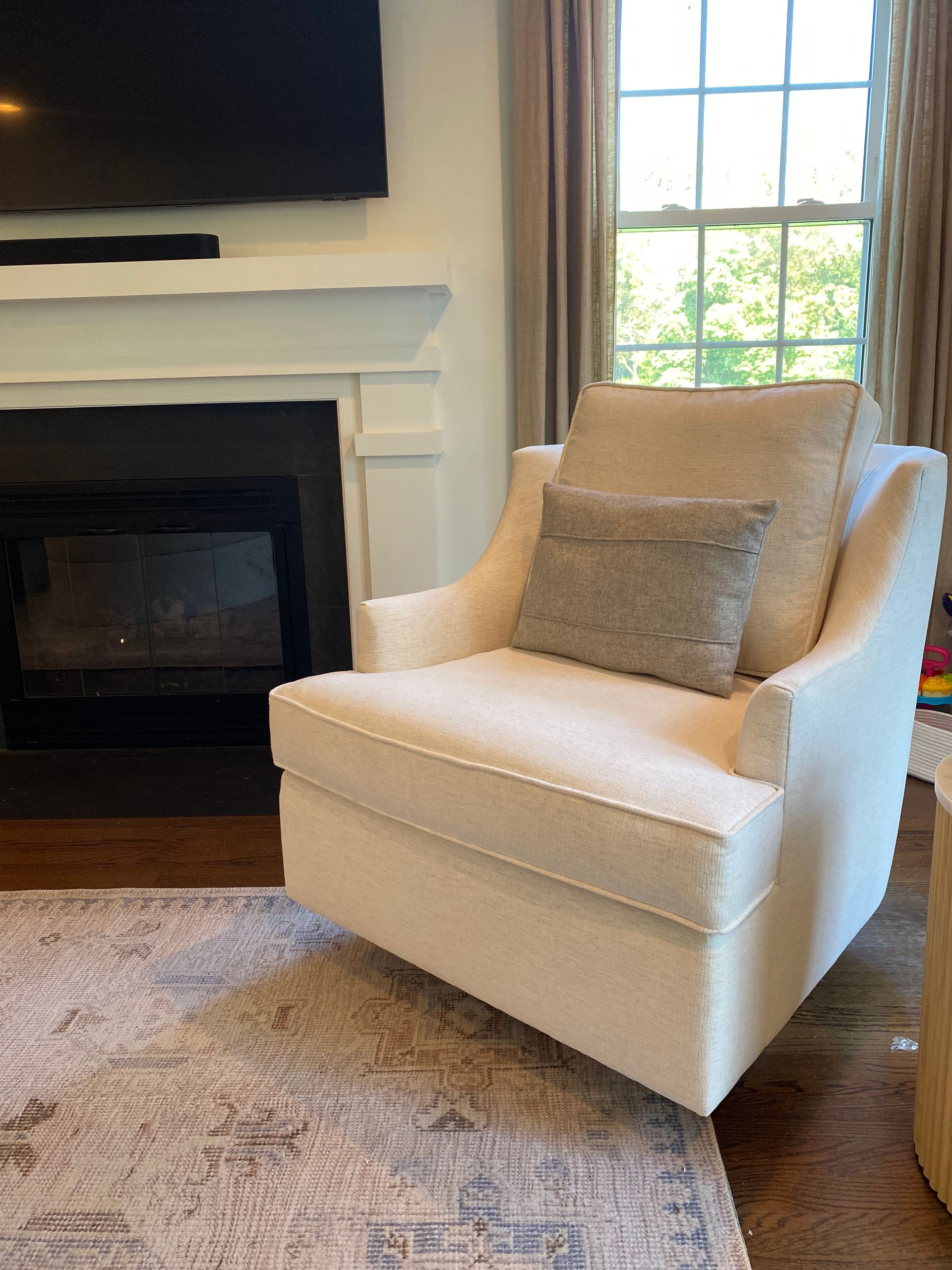 a white chair is sitting in a living room next to a fireplace | Custom furniture by Christy Martin
