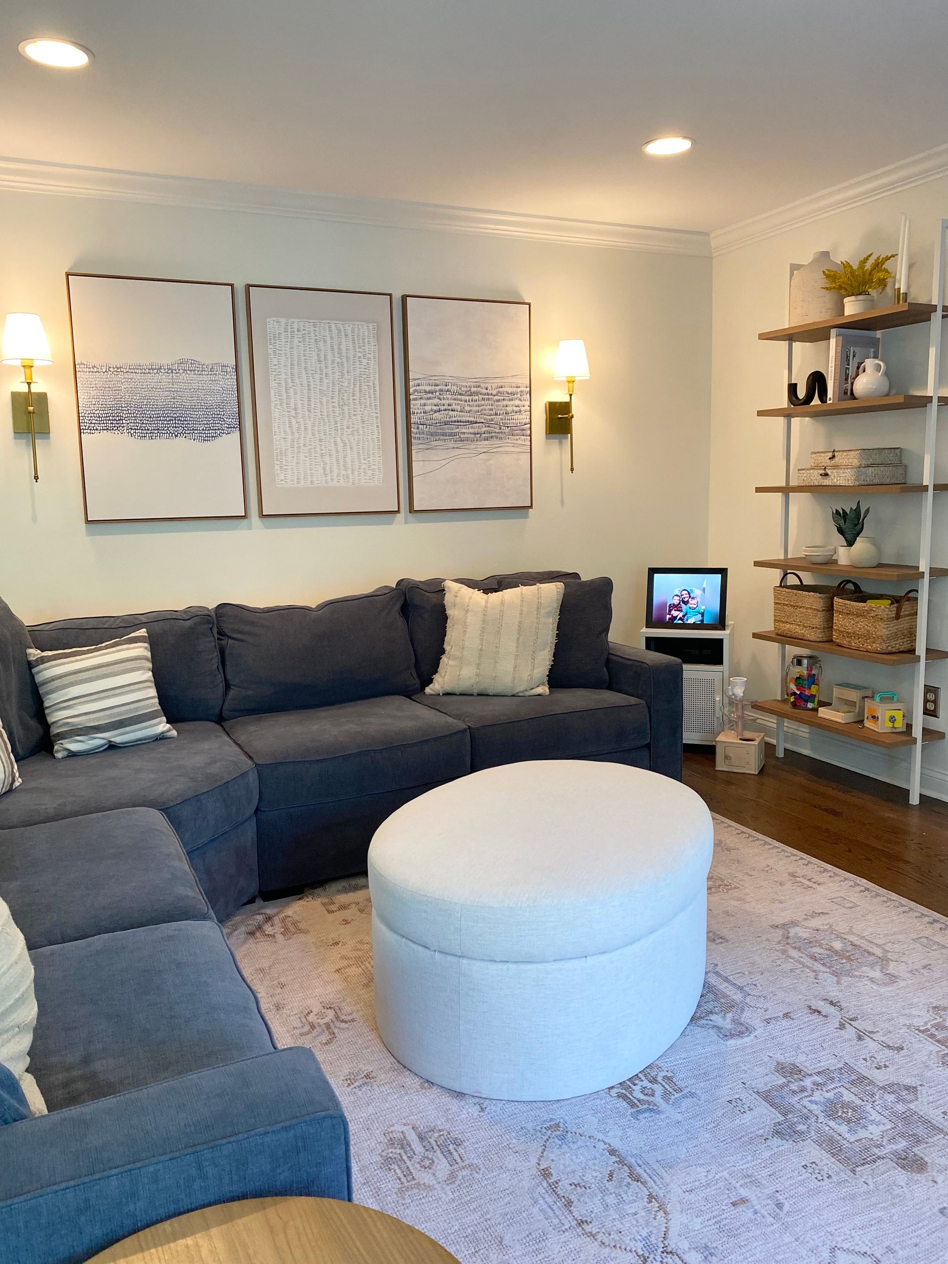 a living room with a couch , chair , ottoman , and television .