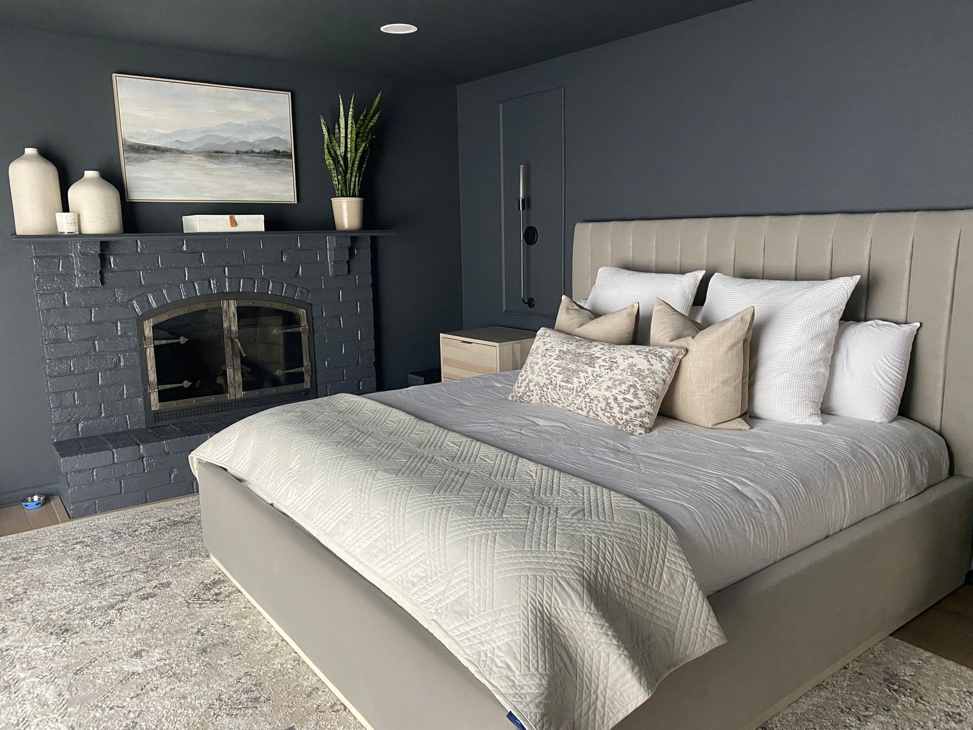 Stylish gray bedroom with a large bed, dark brick fireplace, and soft neutral decor