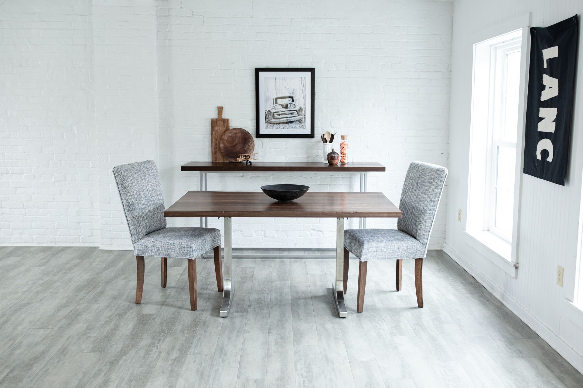 Minimal dining room with a wooden table, gray chairs, and a bright window.
