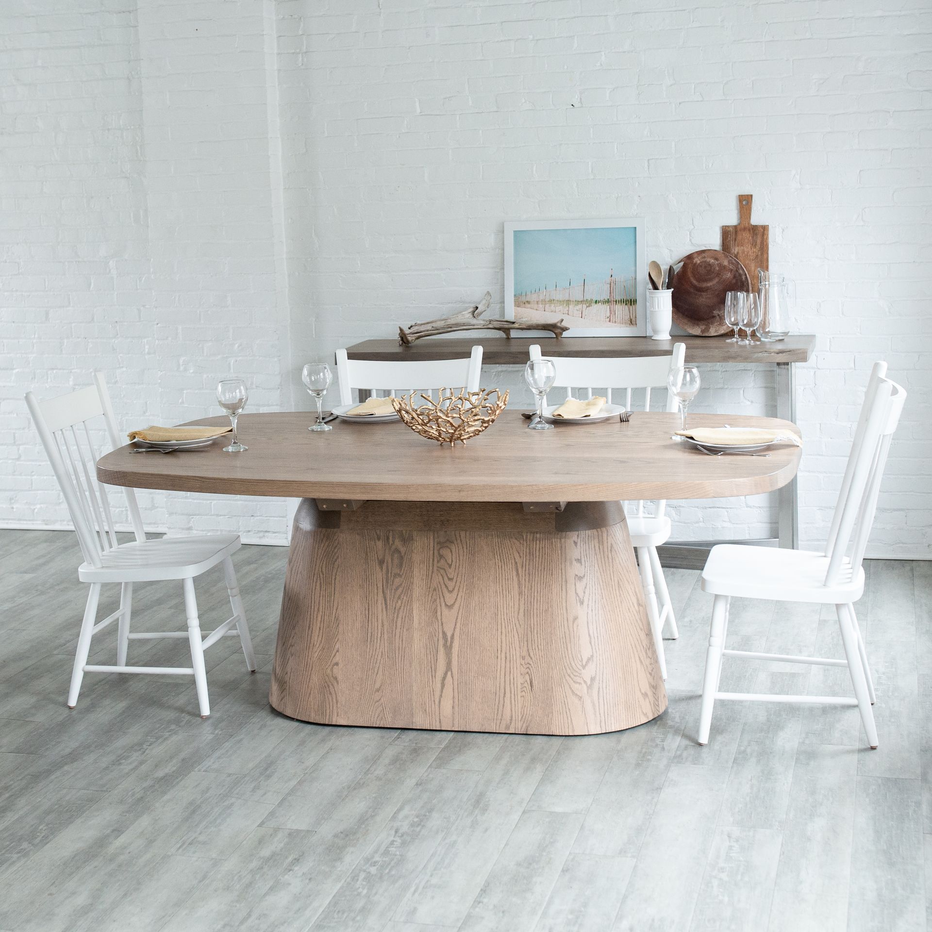 Rustic dining table with white chairs and decor in a bright minimalist room