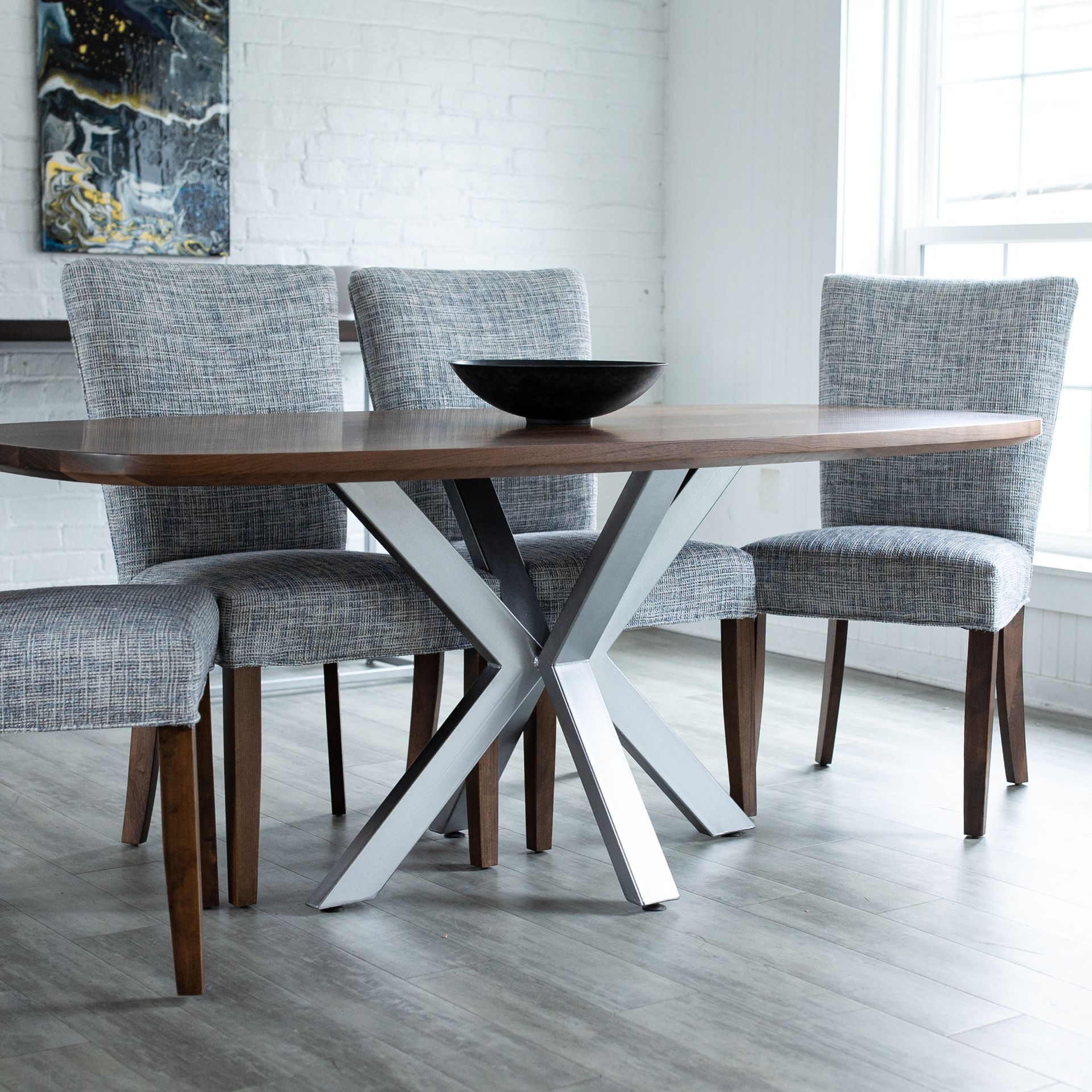 Modern dining table with four gray upholstered chairs in a bright room with a large window