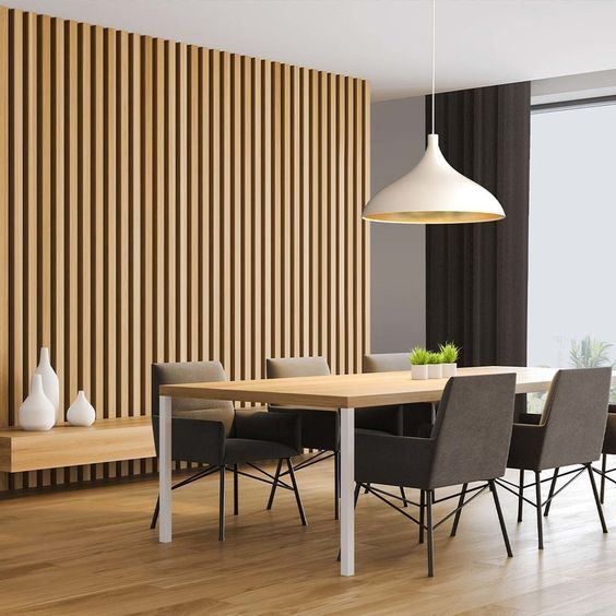 Modern dining room with wooden slat wall, table, chairs, and pendant light in a bright interior