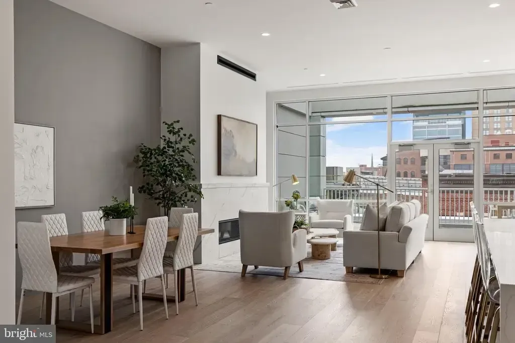 Bright modern living-dining room with white chairs, wood floors, plants, and floor-to-ceiling windows city view
