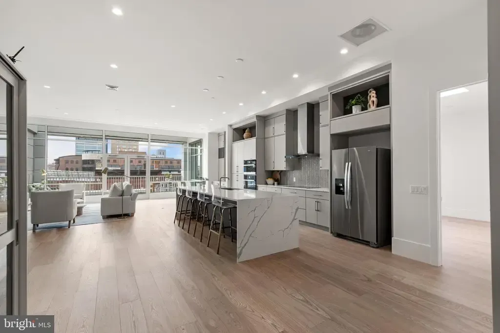 Modern open-concept kitchen and living area with white cabinets, wood floors, and island seating