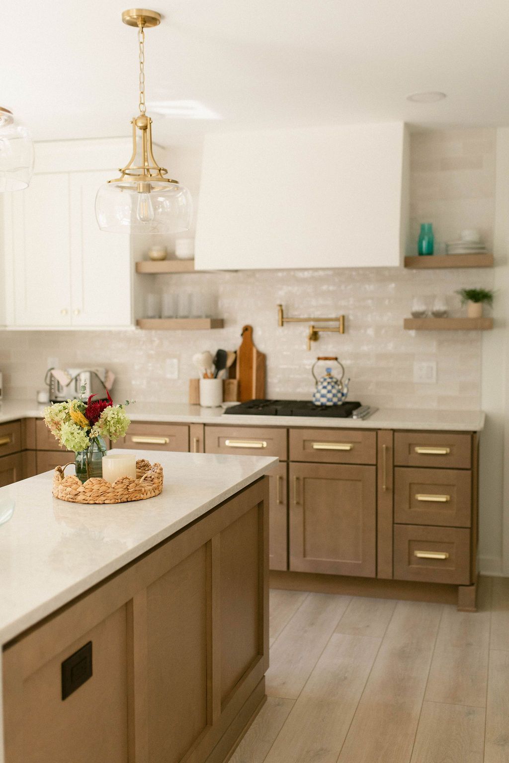 Bright modern kitchen with white cabinets, wood island, and brass accents
