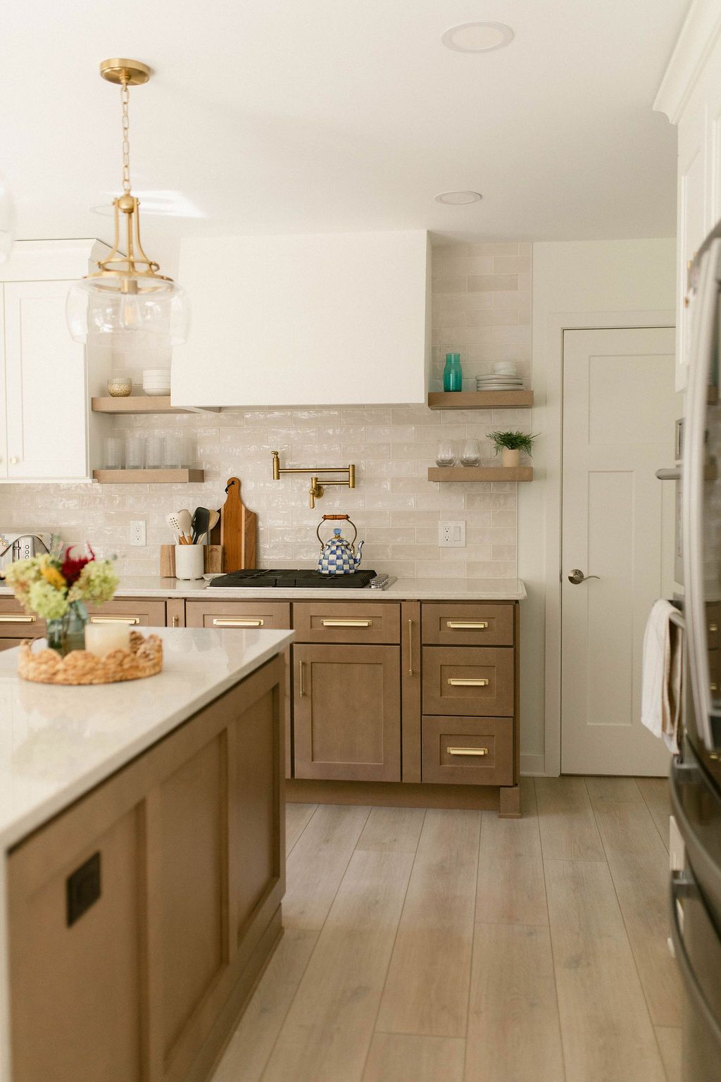 Bright modern kitchen with wood cabinets, white countertops, island, and stainless steel fridge