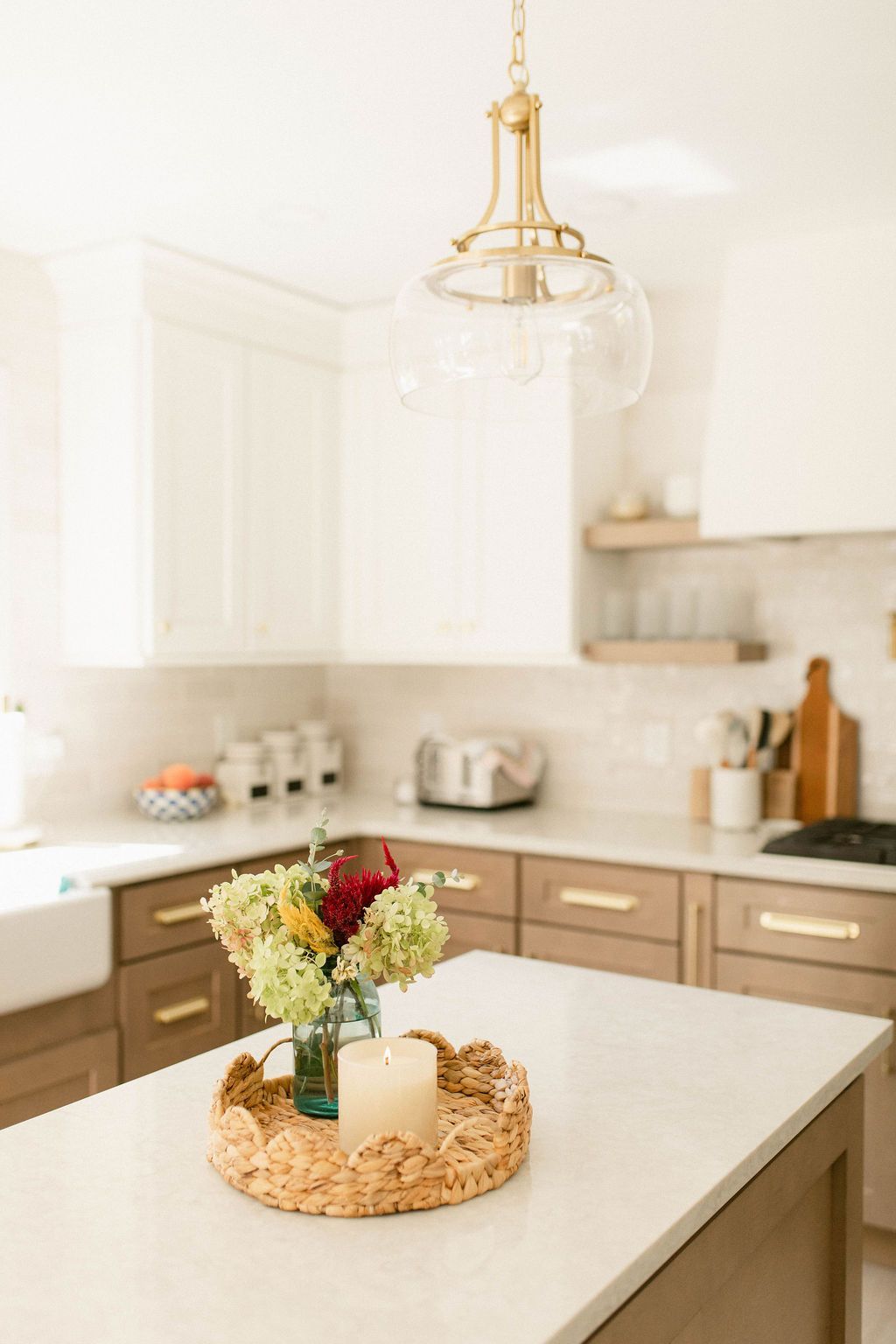 Bright white kitchen with a wooden island and a floral centerpiece on a woven tray.