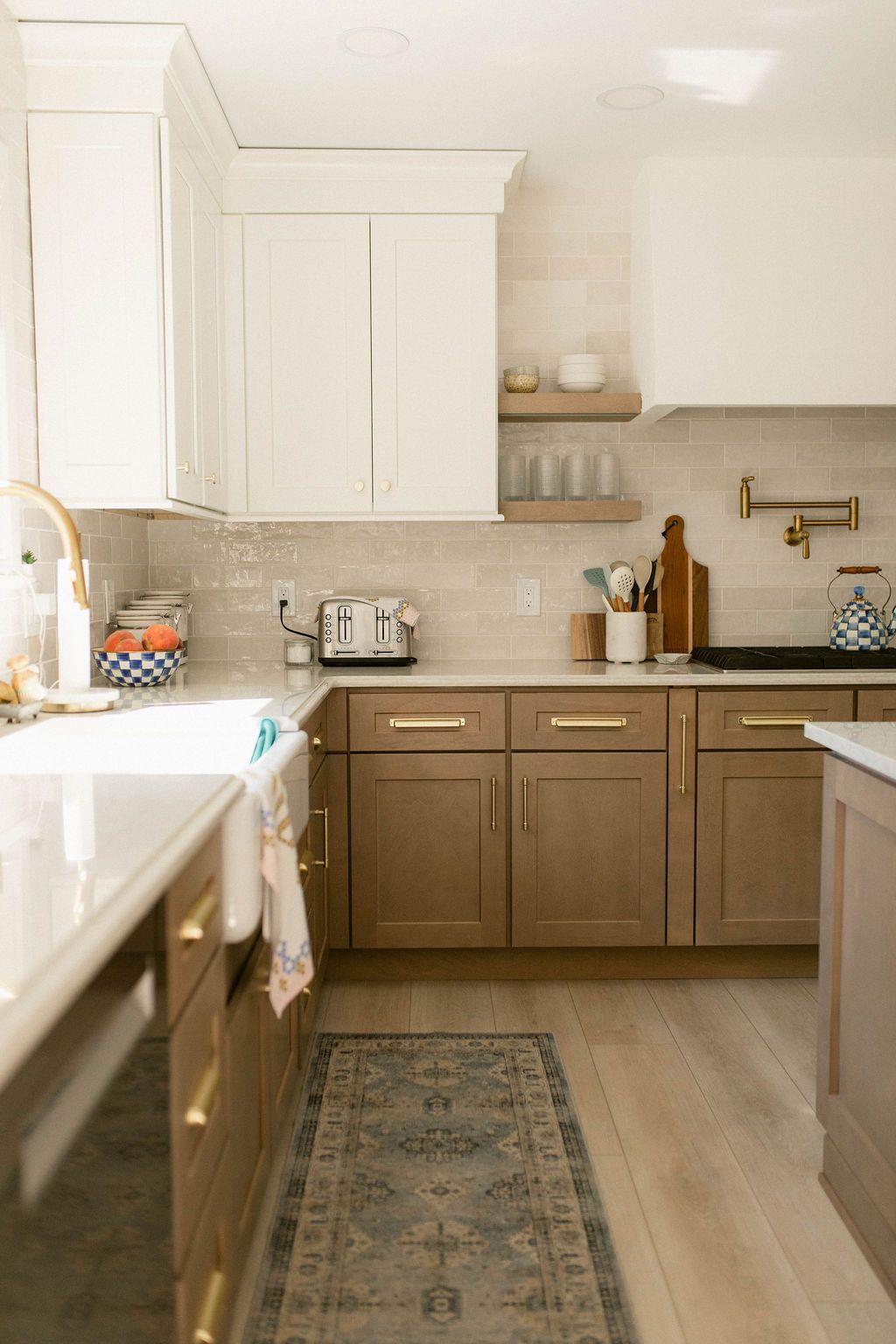 Bright modern kitchen with white cabinets, wood lower cabinets, and a patterned runner rug.