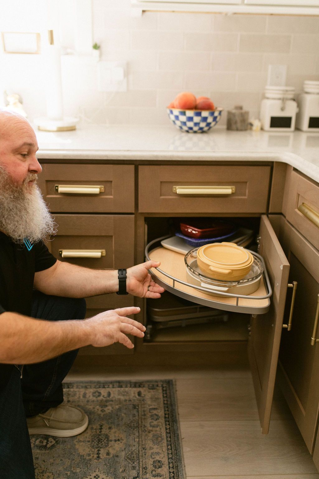 Man loading a tray of stacked pancakes into an open oven in a kitchen