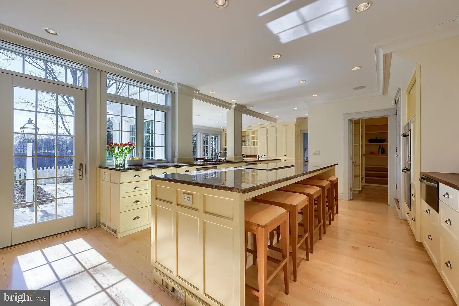 Bright modern kitchen with island seating, large windows, and light wood floors