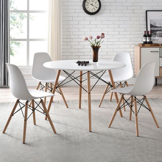 Modern dining room with white round table, four white chairs, and a vase of flowers near a window