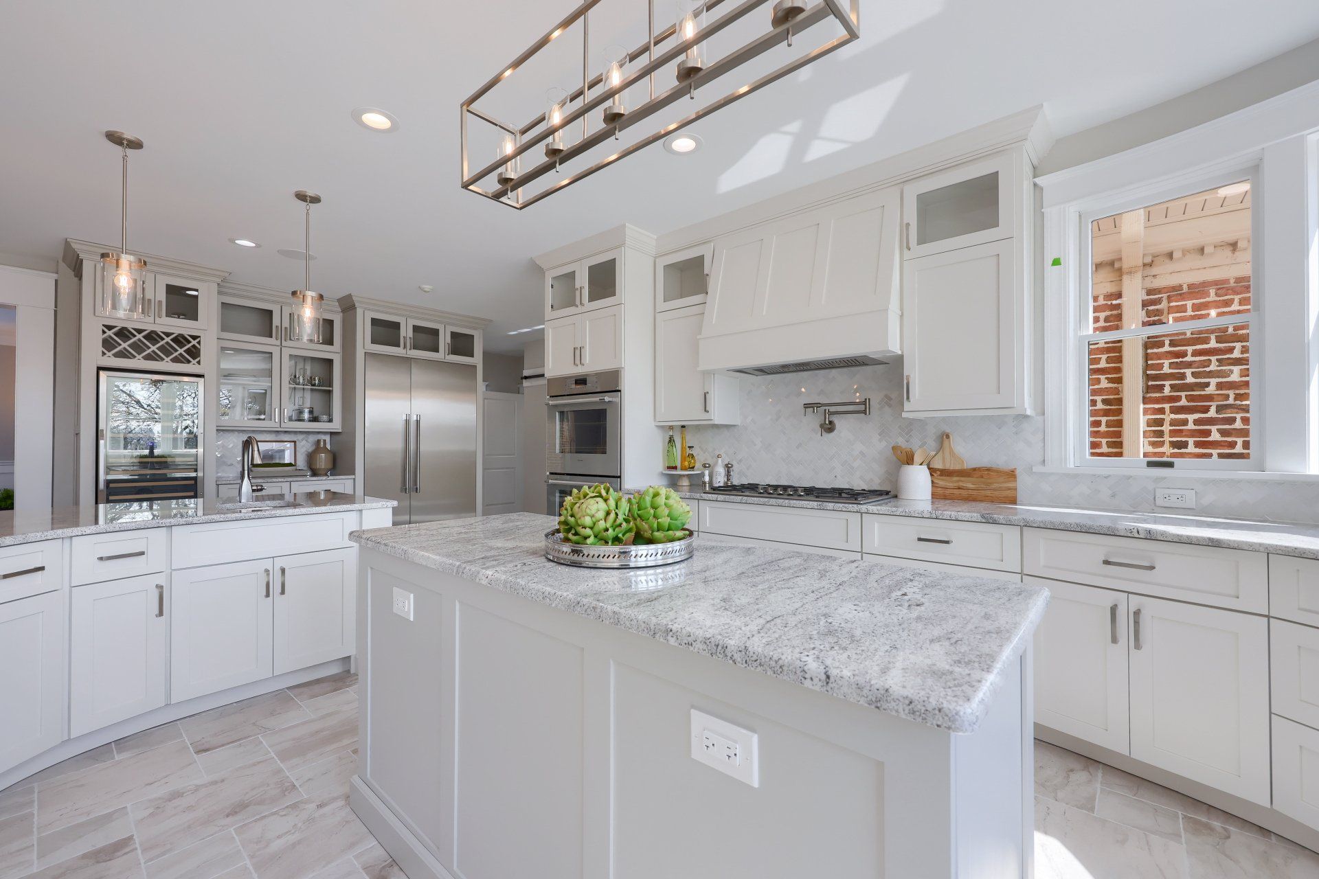 Bright white modern kitchen with island, stainless appliances, and large windows