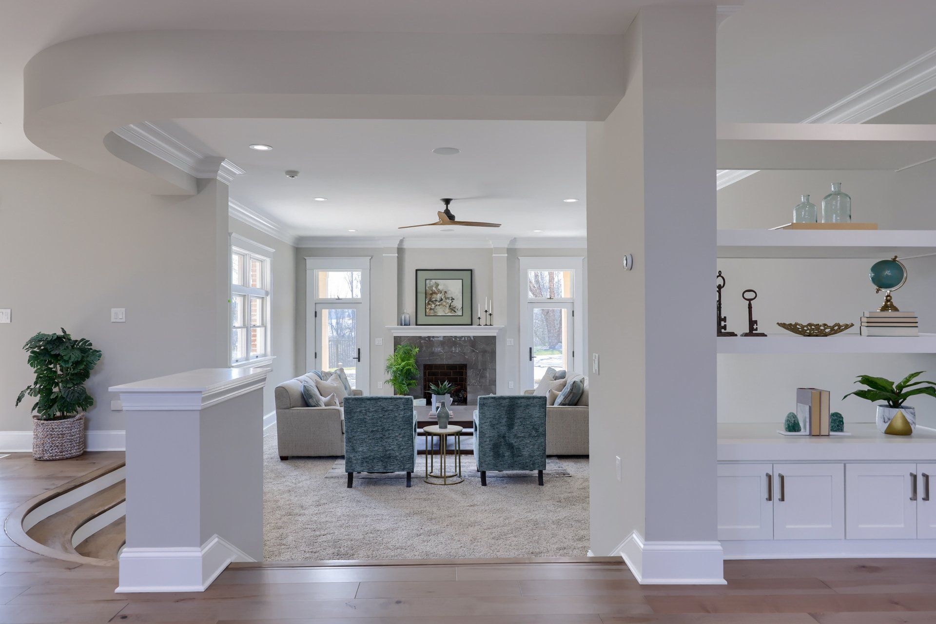 Bright open living room and dining area with white walls, gray chairs, fireplace, and built-in shelves.