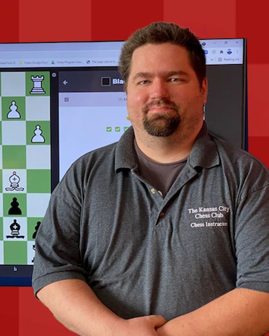 A man wearing a grey shirt with the kansas city chess club embroidered on it