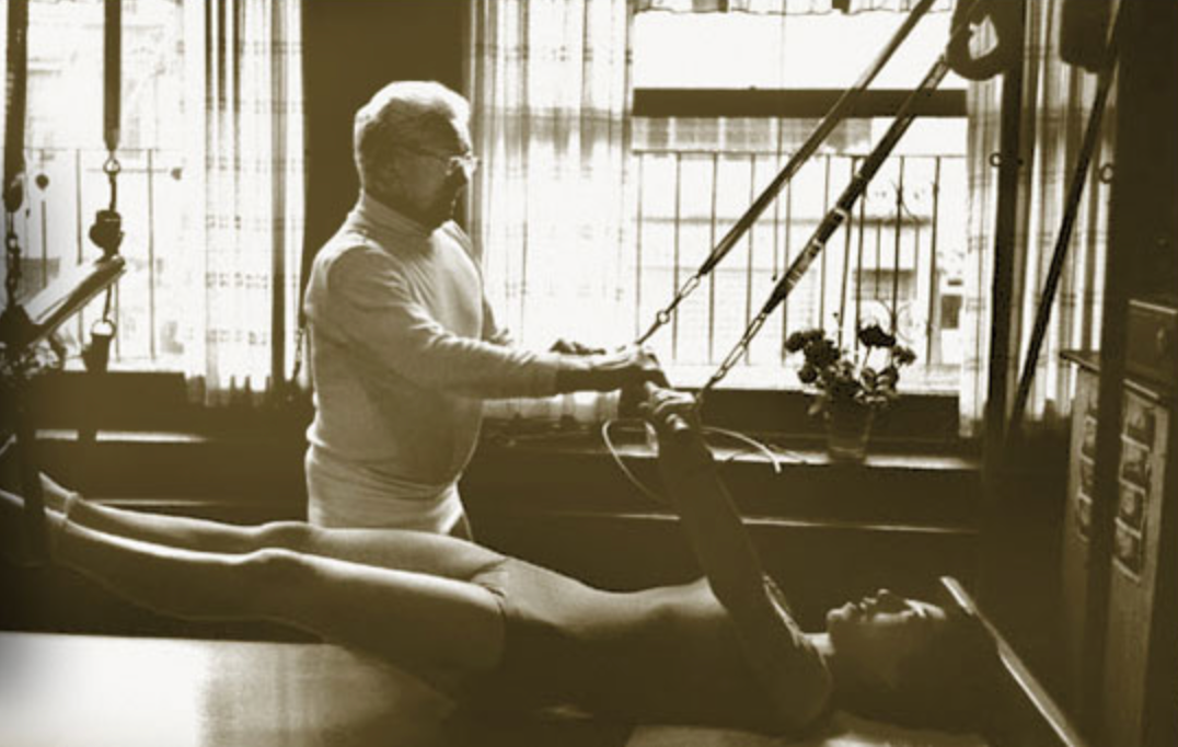 A therapist works with a client on a massage table in a bright studio with large windows.
