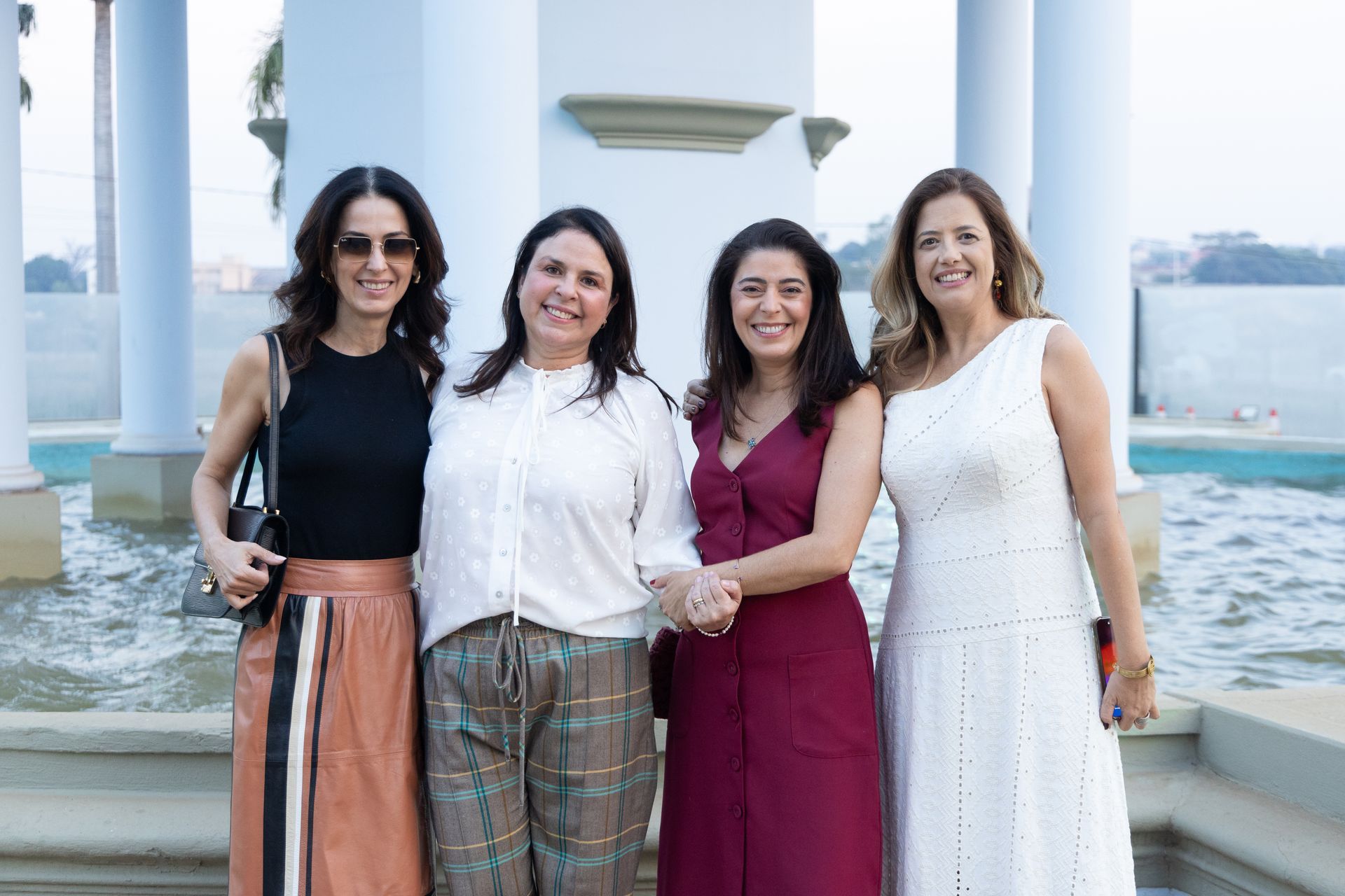 Quatro mulheres estão posando para uma foto em frente a uma fonte.