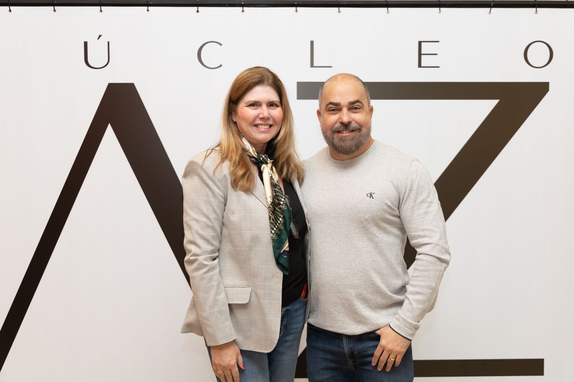 Um homem e uma mulher estão posando para uma foto em frente a uma placa.