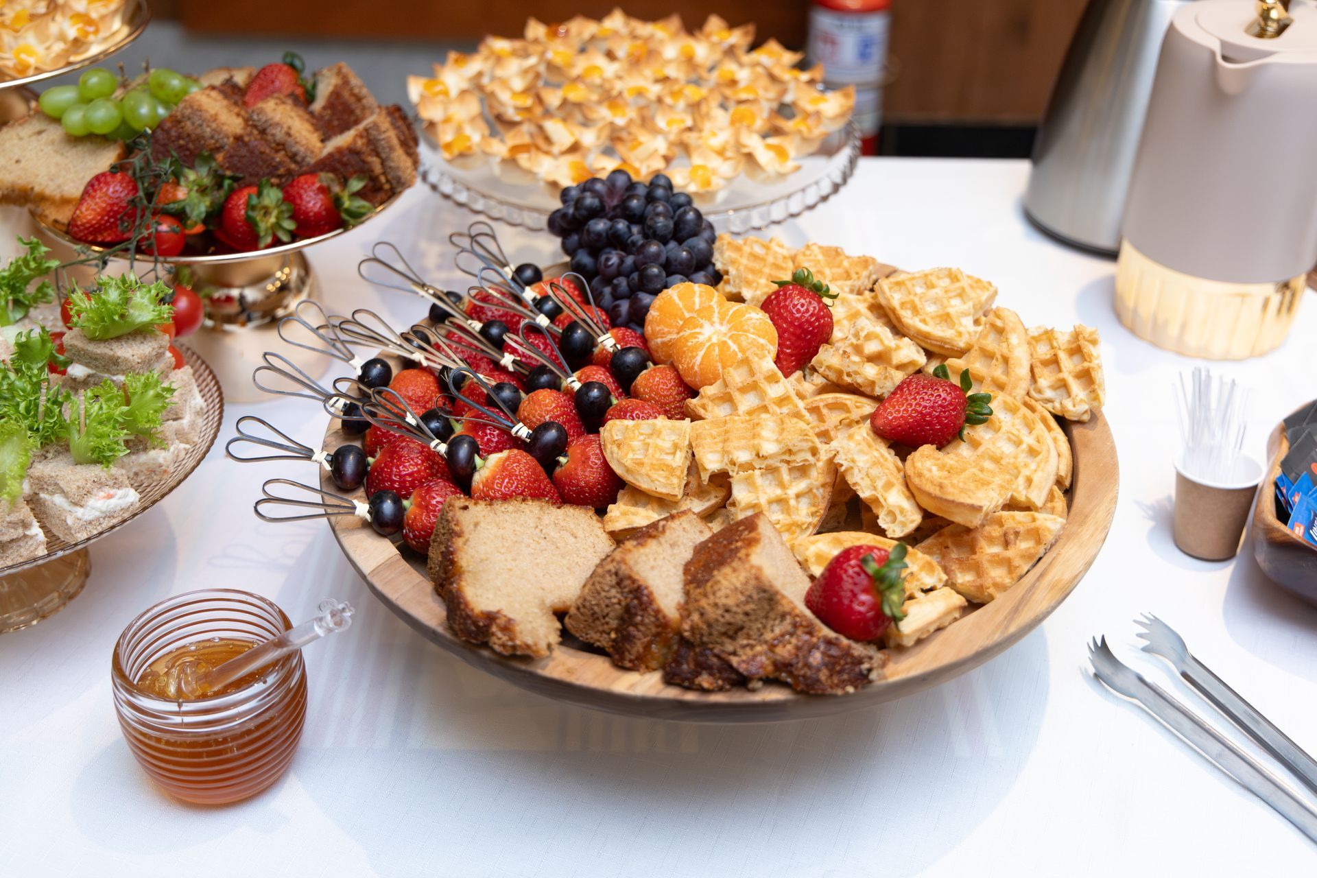 Uma mesa coberta com uma variedade de comidas, incluindo uma bandeja de frutas e pão.