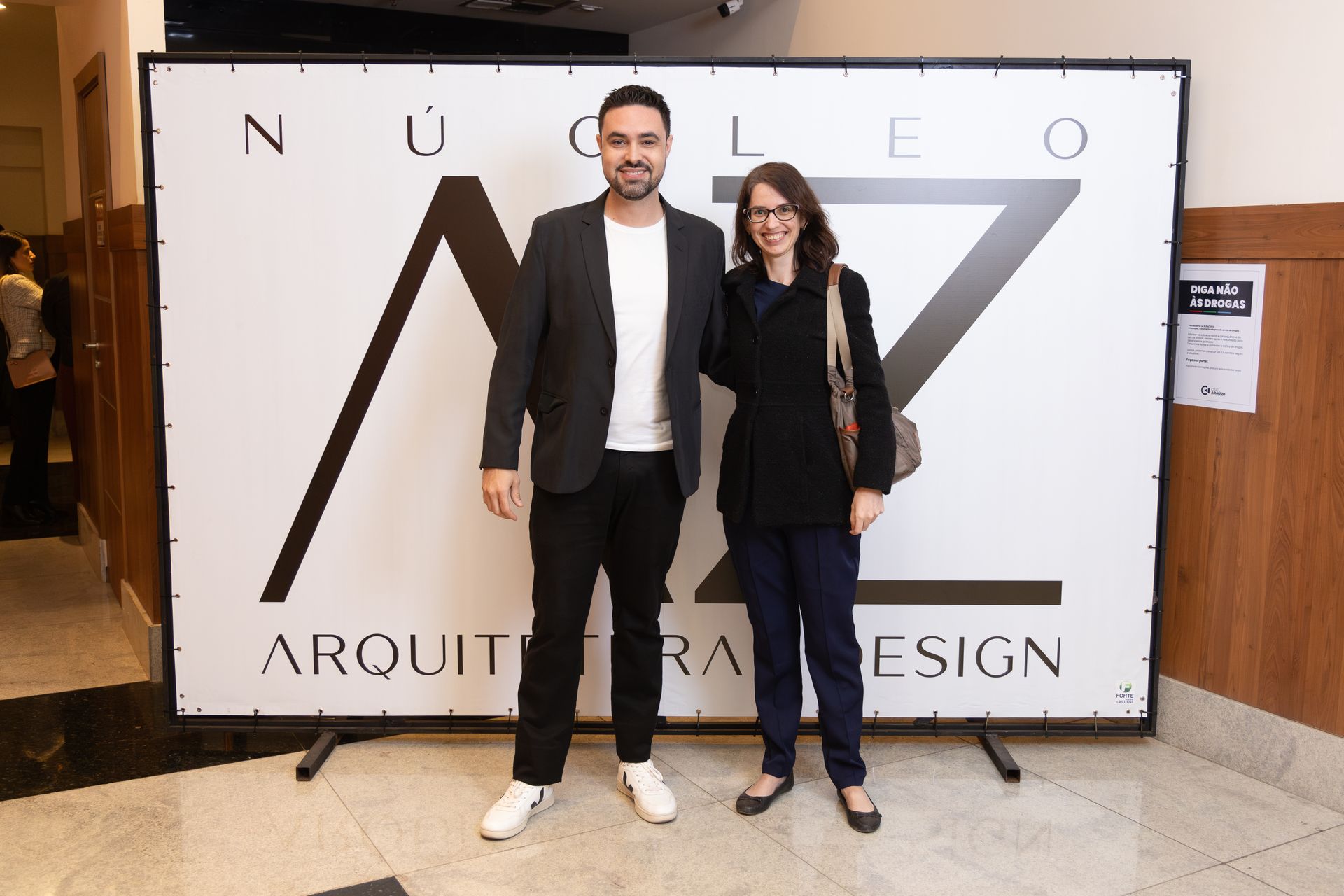 Um homem e uma mulher estão em frente a uma placa que diz arquiteta design.