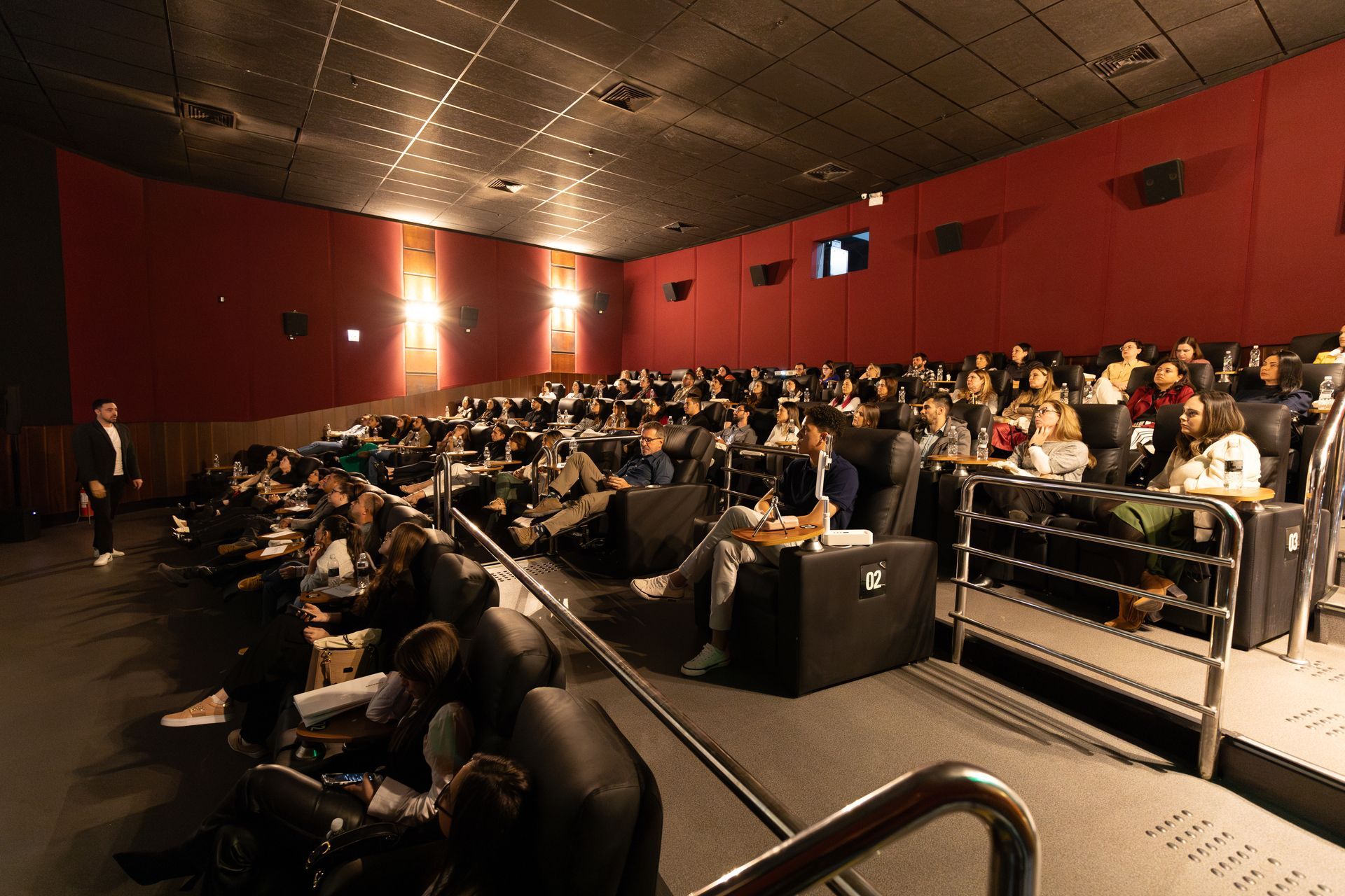 Um grande grupo de pessoas está sentado em um cinema assistindo a um filme.