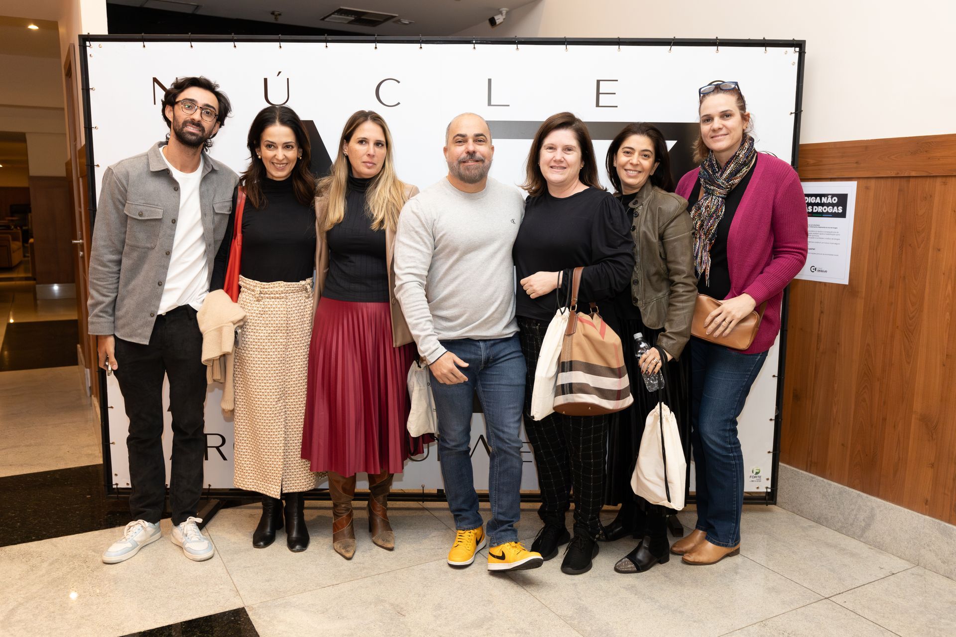 Um grupo de pessoas está posando para uma foto em frente a uma parede.