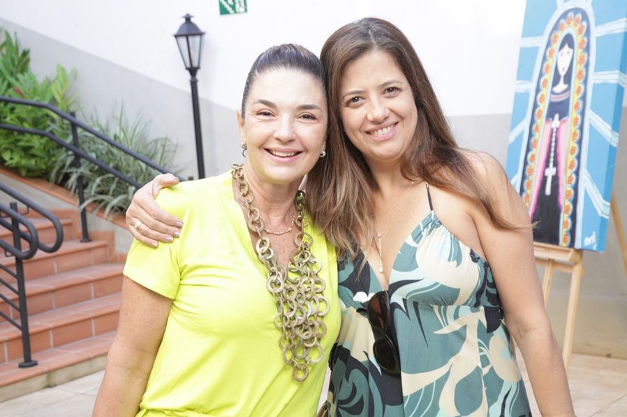 Duas mulheres estão posando para uma foto juntas em frente a uma escada.